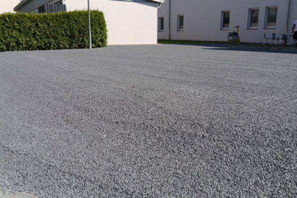 Mit Splitt befüllte ECORASTER Fläche umgeben von weißen Gebäuden