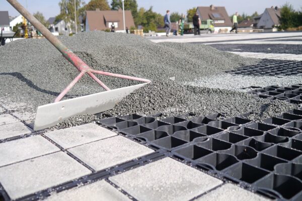 Kies wird mit großflächig mit einer Schaufel in die ECORASTER Bodengitter verteilt.