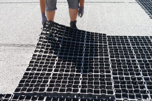 Arbeiter legt eine Lage ECORASTER auf den Boden ab.